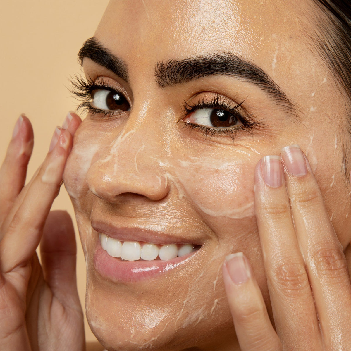 Woman smiling while massaging a foaming cleanser over her face