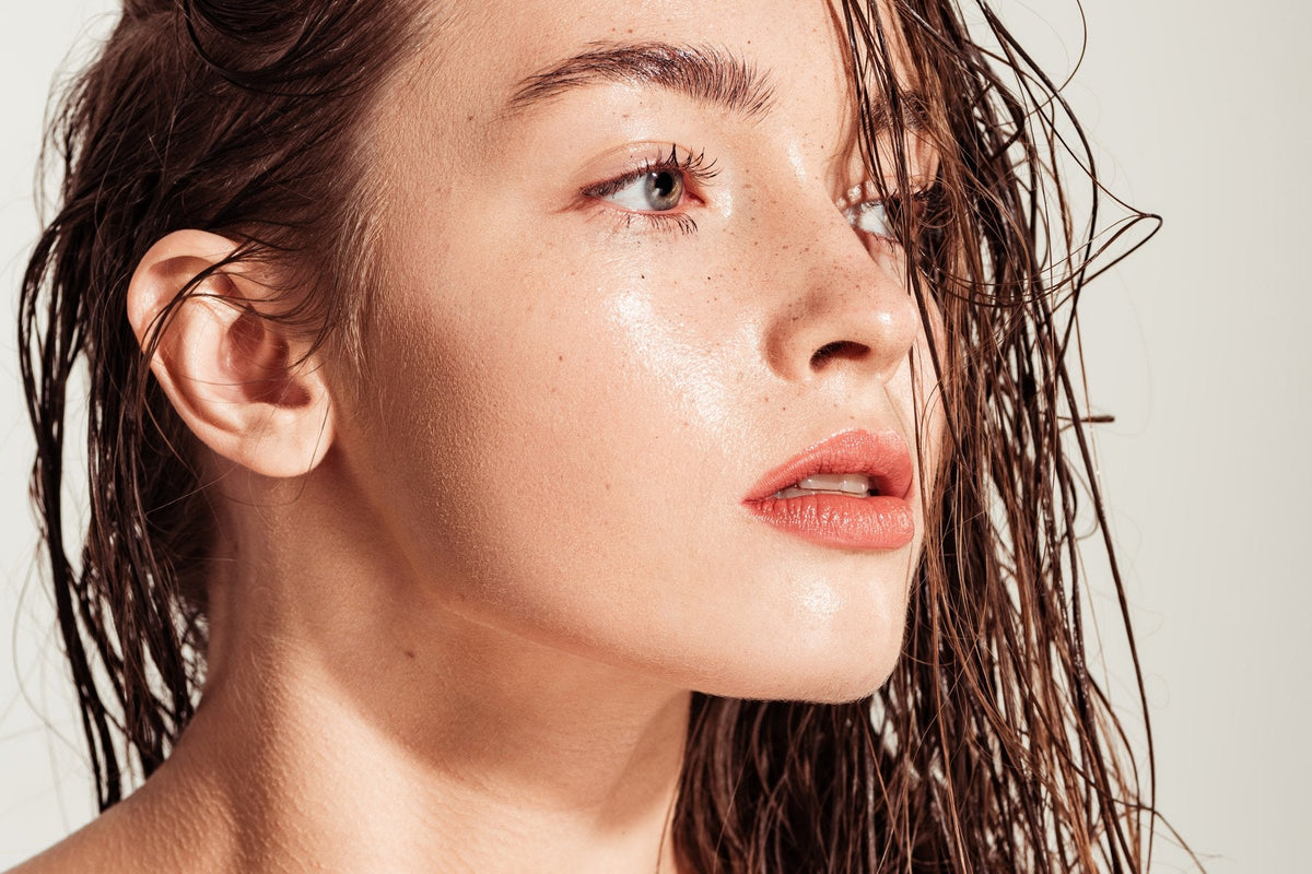 Bare luminous skin with damp hair swept back