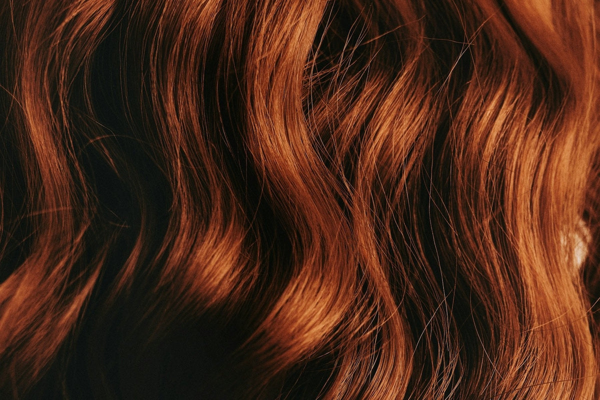 Glossy auburn waves against a warm background
