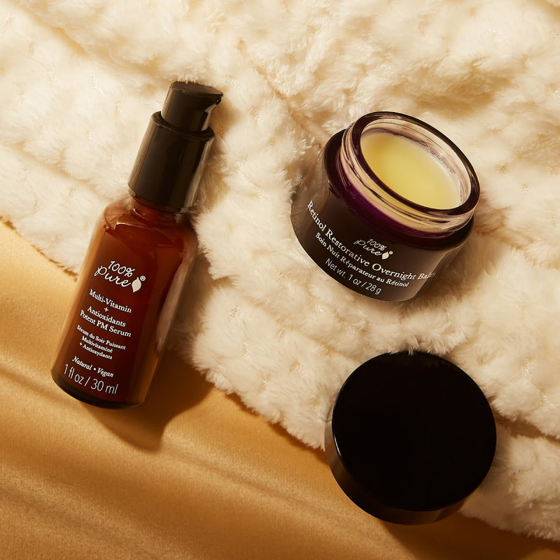 100% Pure amber pump bottle and an open jar of balm resting on a cream fleece blanket