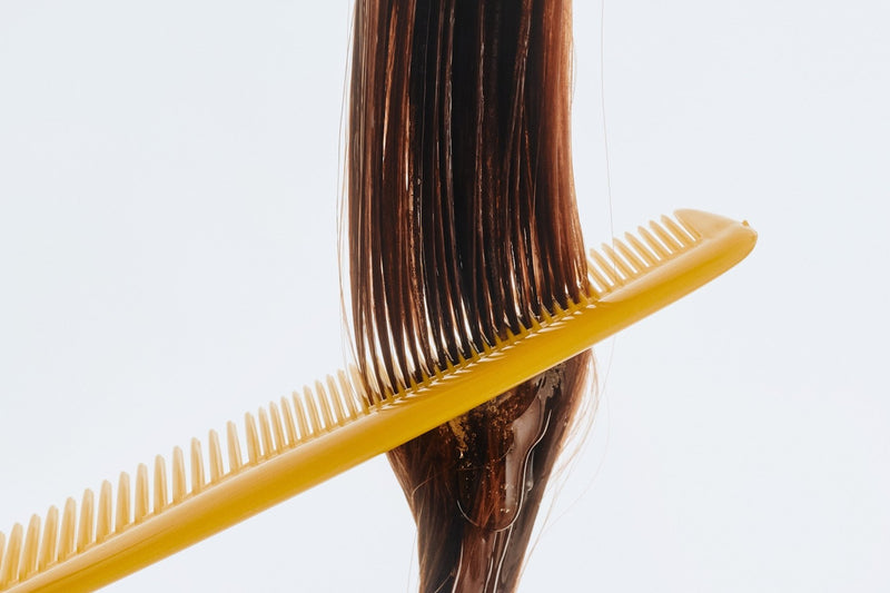 A wide-tooth comb drawn through long smooth hair